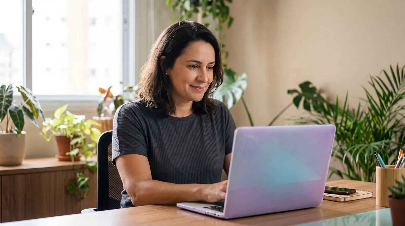 Uma mulher trabalha no notebook em um escritório iluminado, com o brilho do Orbi em sua roupa.